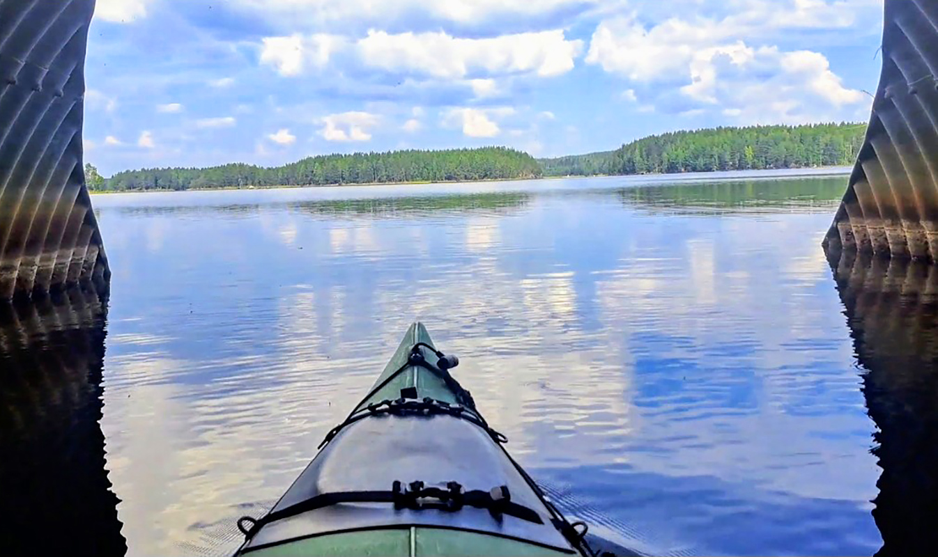 Paddling through a culvert under the road on a calm lake.
