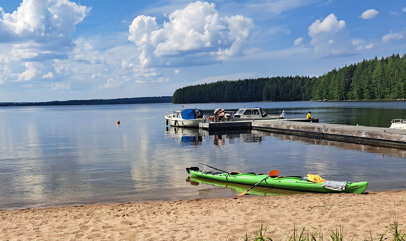A canoe has been pulled up onto the sandy beach beside the pier. Several boats are moored at the pier.