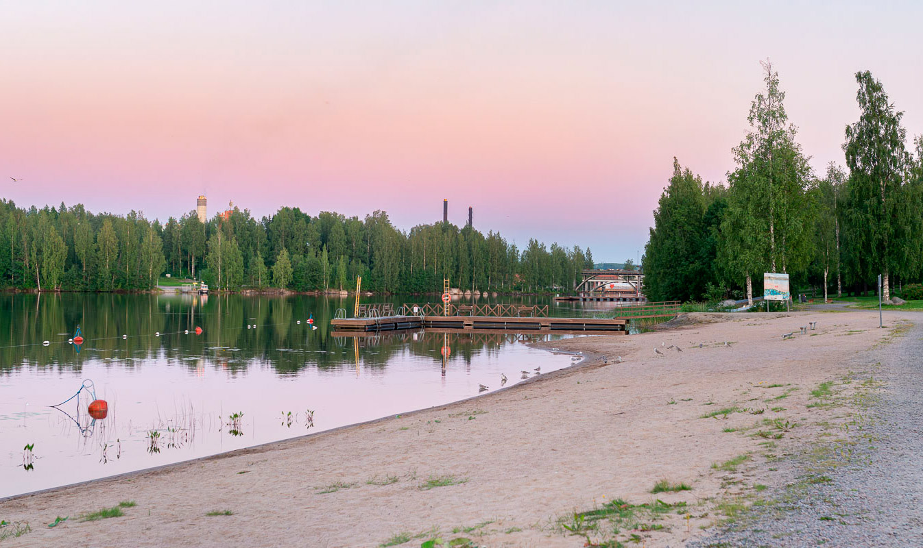 The sandy beach of Äänejärvi, a mirror-calm lake and a sky tinted violet by the sunset.