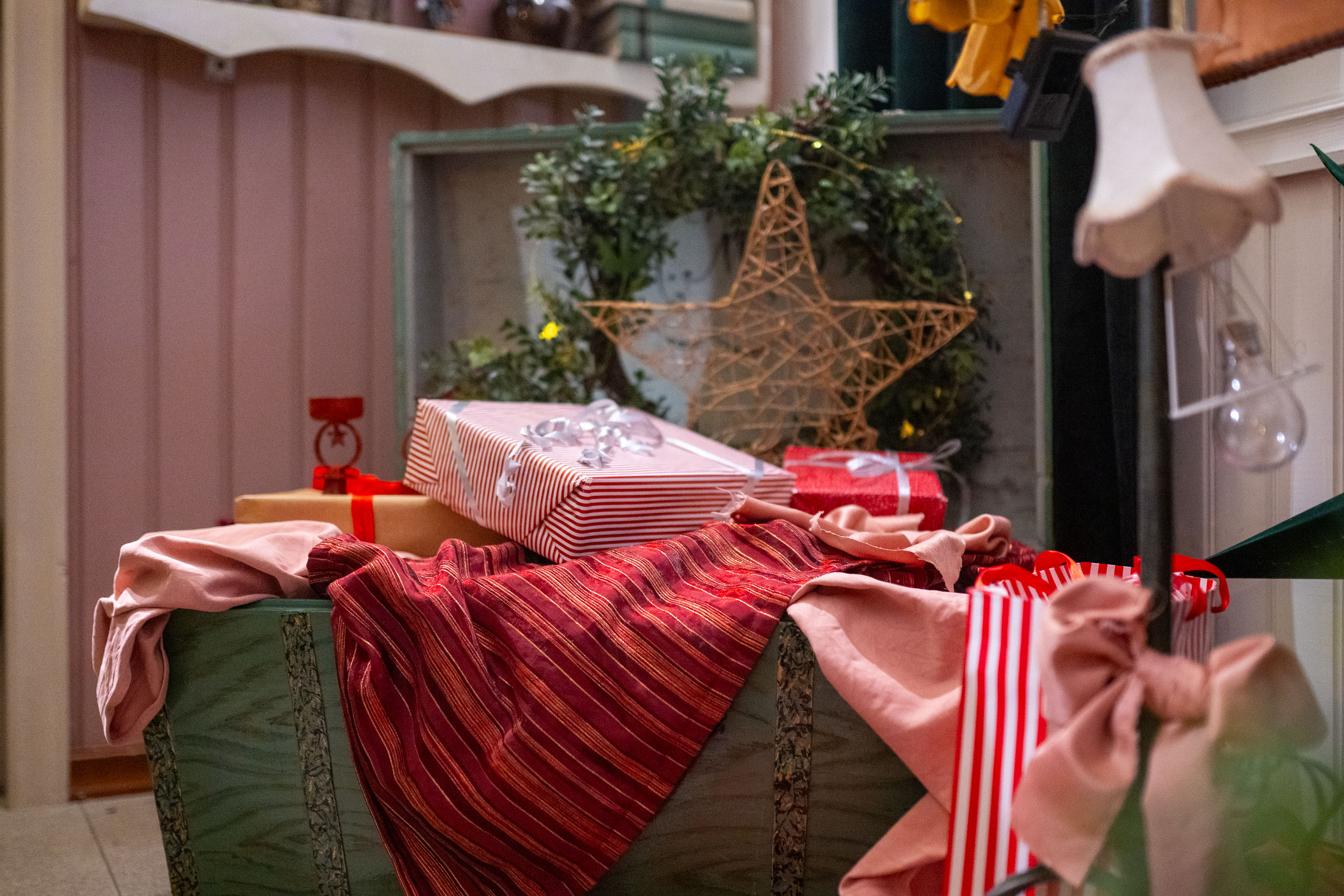 In a wooden chest, gift packages and a wreath on top of fabrics.