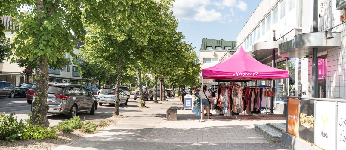 On a summer street, a pop-up sales point where a person is looking at products.